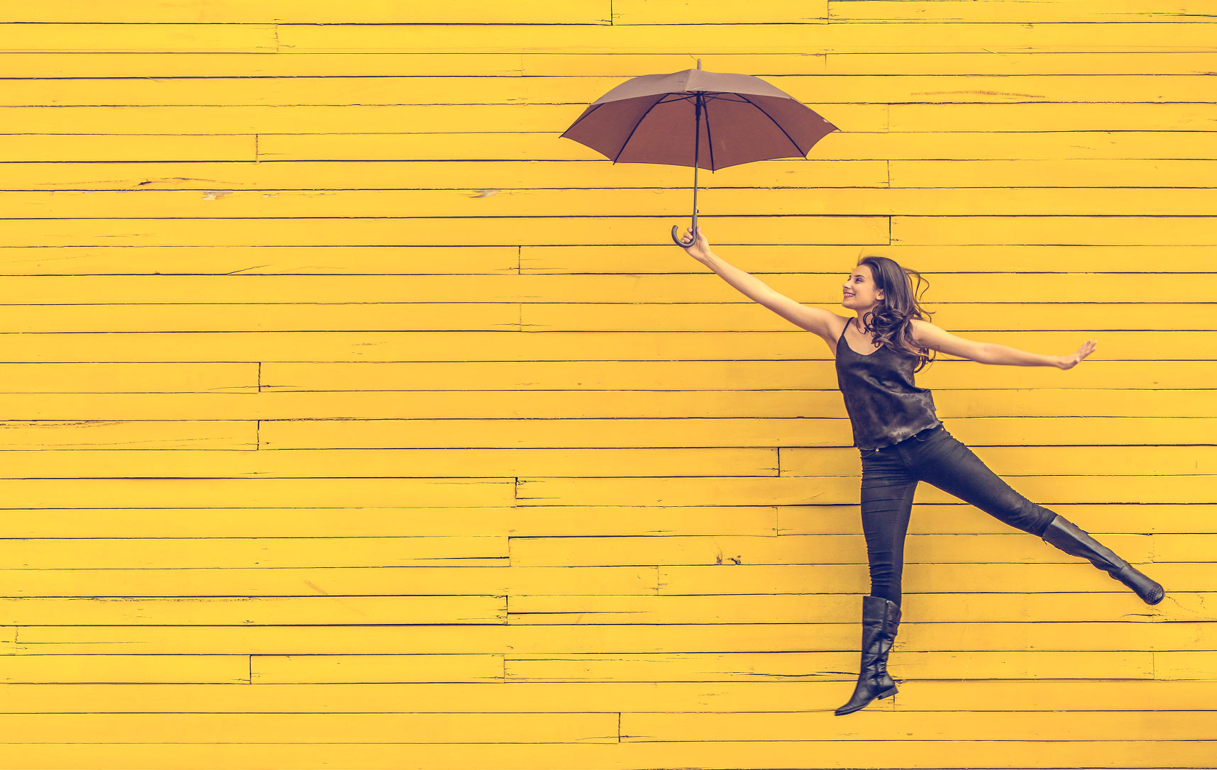 Frau mit Regenschirm vor gelbem Hintergrund